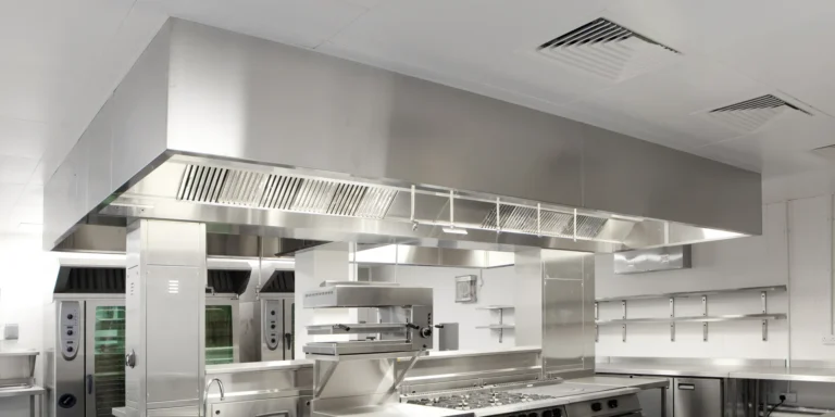 Cocina industrial con campana de centro y línea de cocción en acero inoxidable
