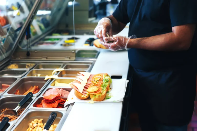 Cocinero preparando alimentos en una línea de montaje de cocina profesional