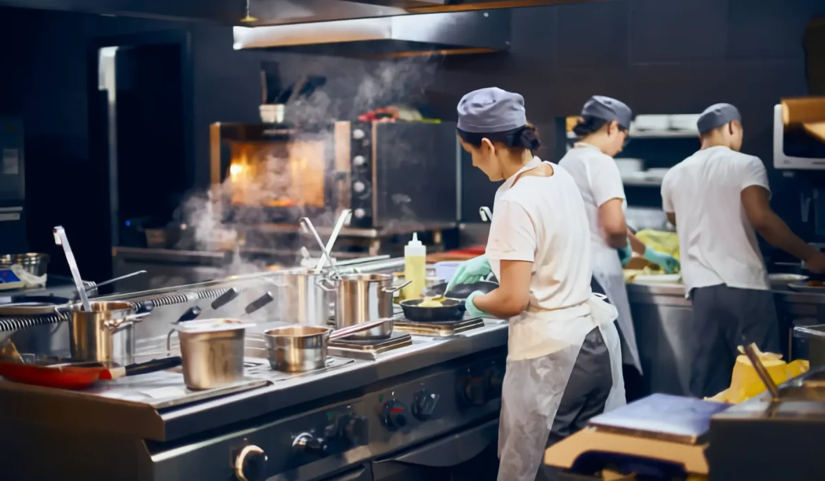 Equipo de cocina trabajando en una línea de cocción con extracción