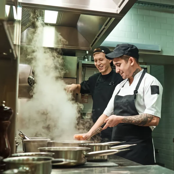 Cocineros trabajando entre el vapor de una cocina profesional