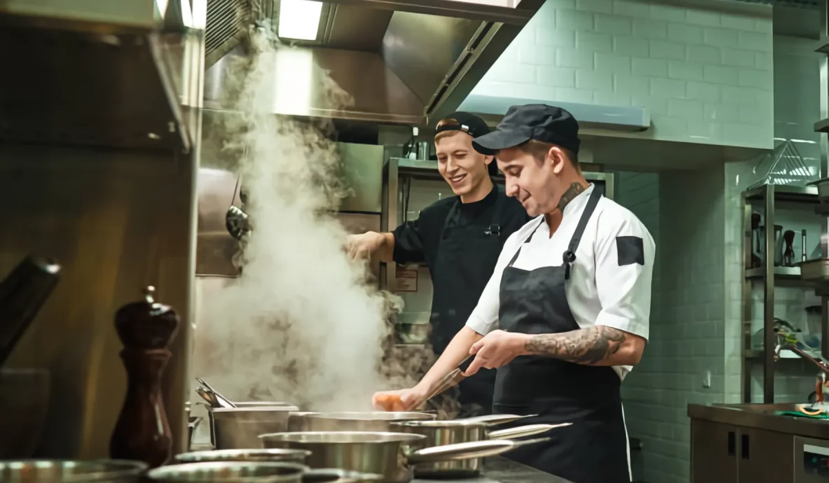Cocineros trabajando entre el vapor de una cocina profesional